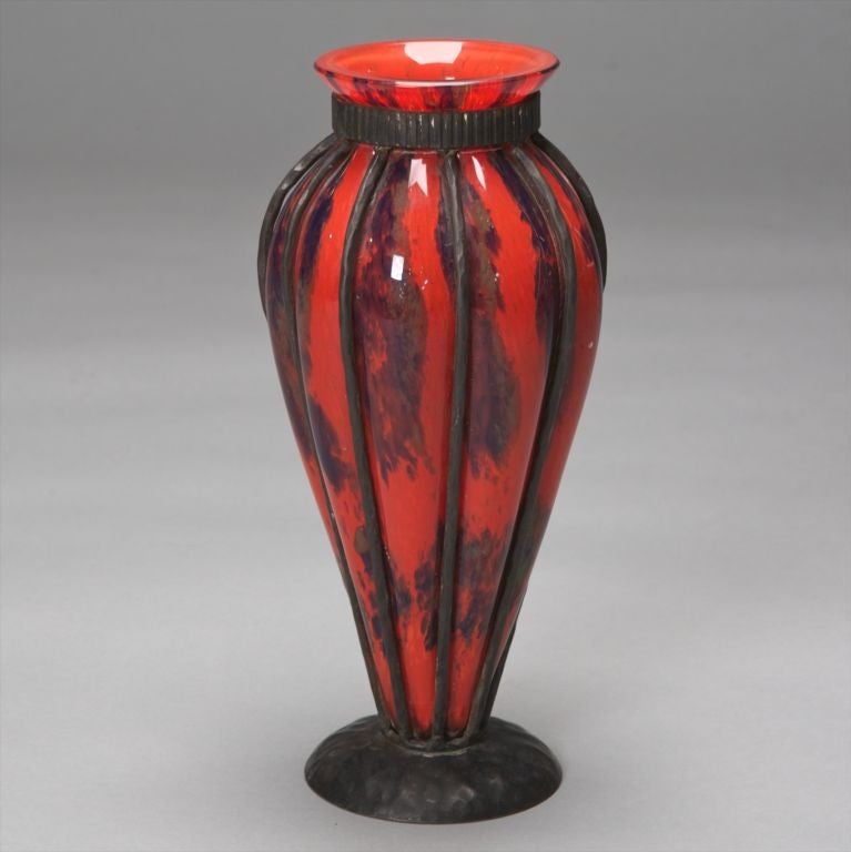 This glass vase is a mottled red with a decorative iron surround and base designed by Pierre D'Avesn.  D'Avesn designed for Daum from 1927-1932 and also supervised the Daum Croismare Glassworks near Luneville which were renamed Verreries D'Art