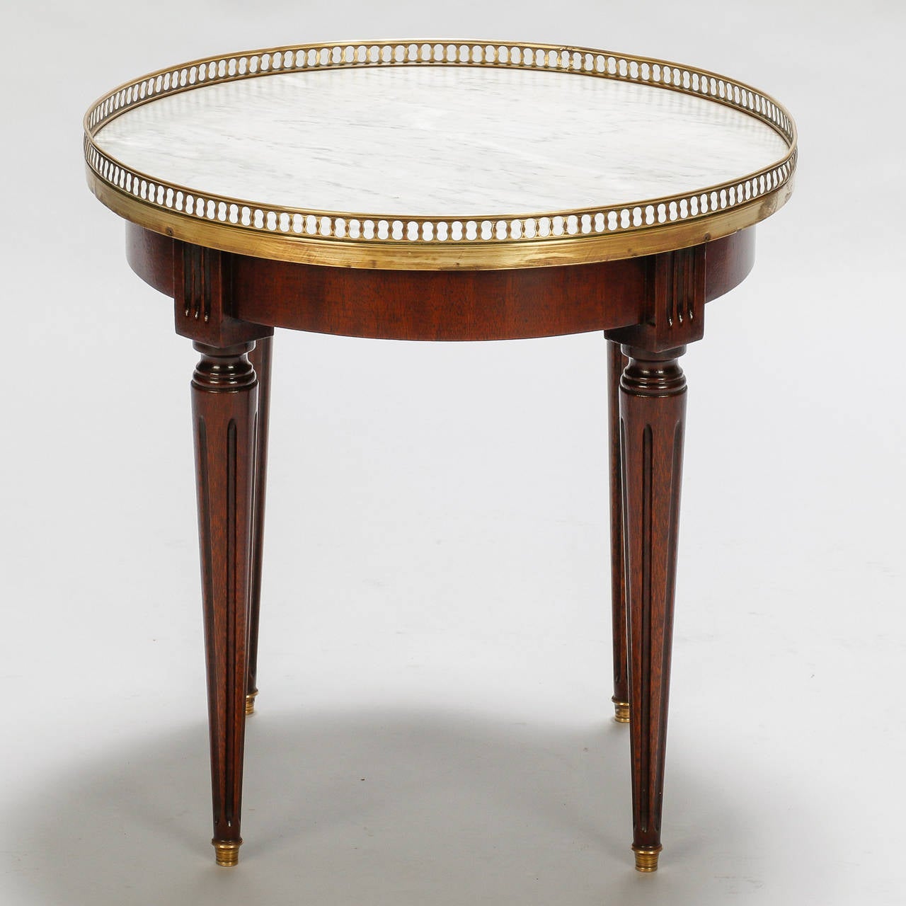 Circa 1920s small round European side table with reeded, tapered legs, a brass gallery and gray and white marble top.