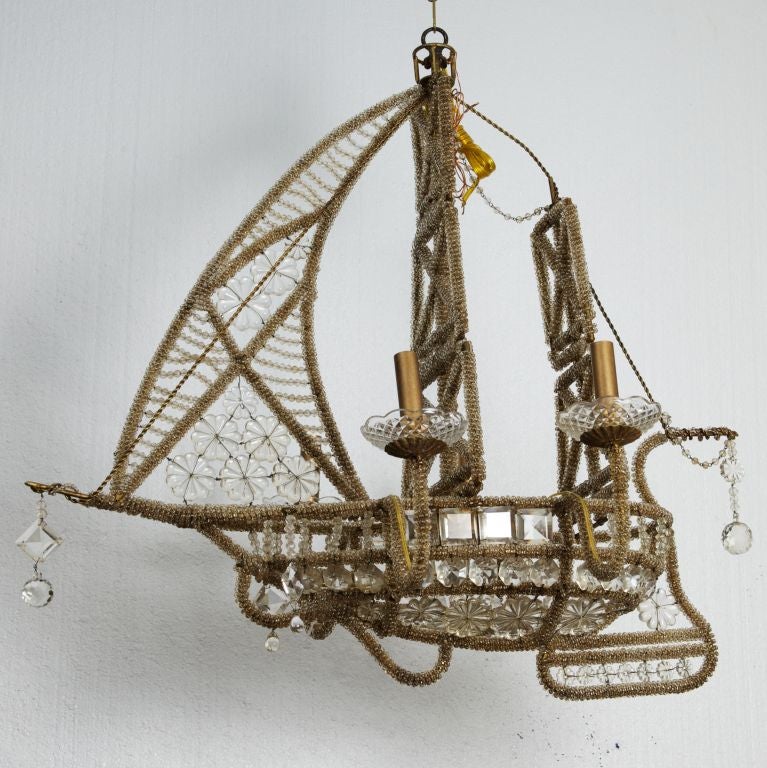 This circa 1930s Italian crystal chandelier has four candle style lights and a brass wire frame in the shape of a sailing ship.  Decorated with crystal beads and pendants - a very striking antique fixture.