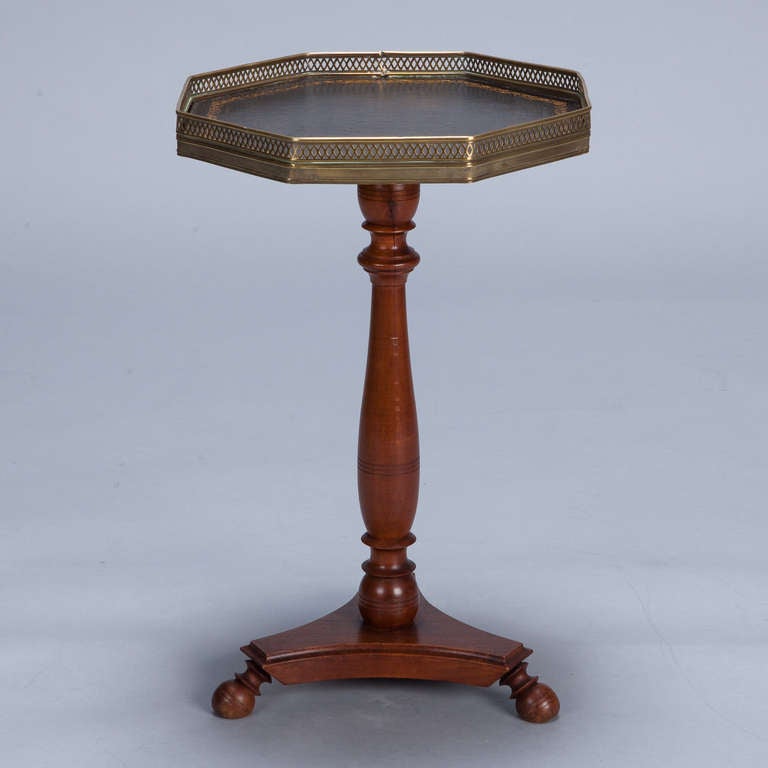 French pedestal side table has a footed wood base, turned support and eight sided black leather table top and brass gallery.