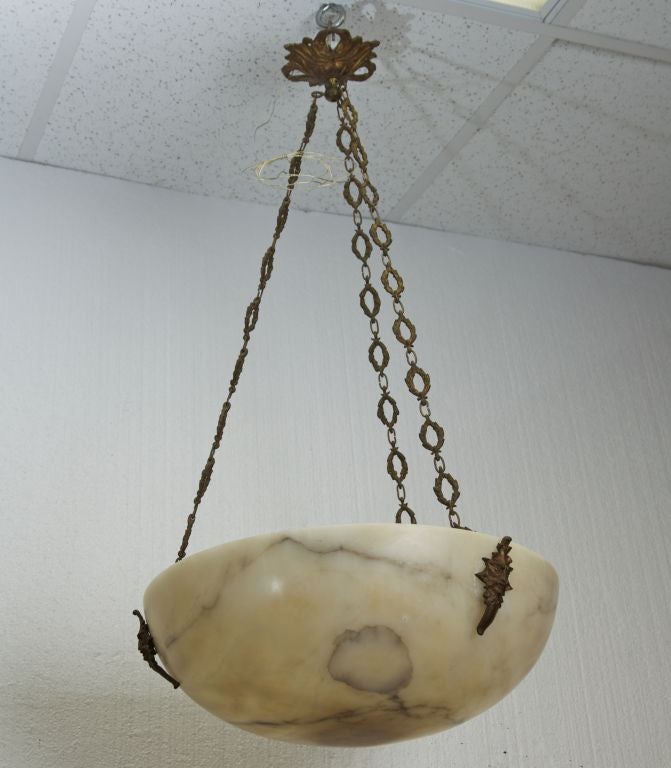 Circa 1920s French hanging fixture with large alabaster bowl. Warm beige with gray veining and bronze hardware. Gargoyle fittings, ornate chain and original ceiling canopy.