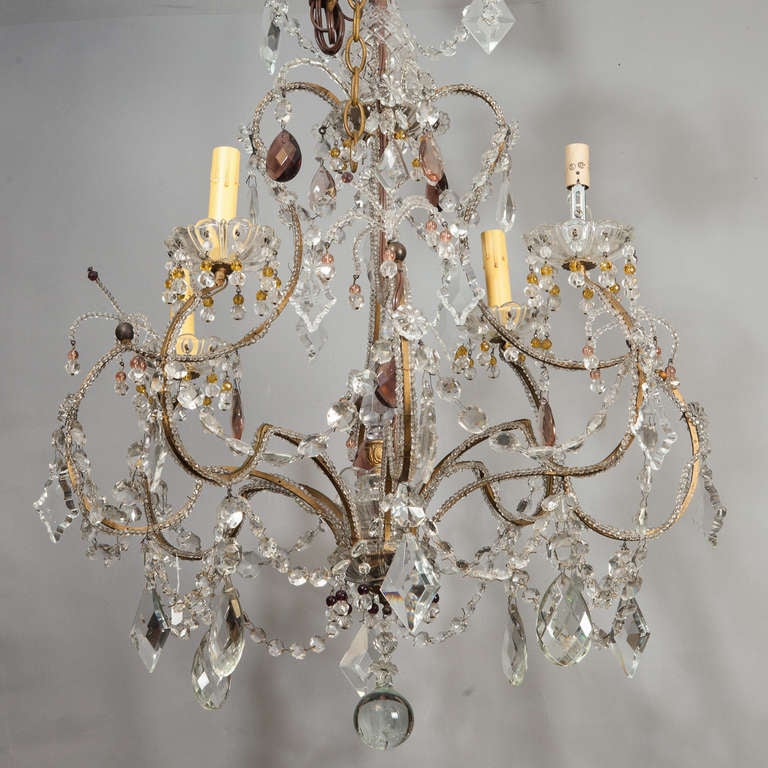 Circa 1920s French chandelier has four candle style lights, a brass cage-form base with clear glass beading, amethyst accents and several large diamond and oval shaped crystal pendants and a large round crystal drop. New wiring for US electrical