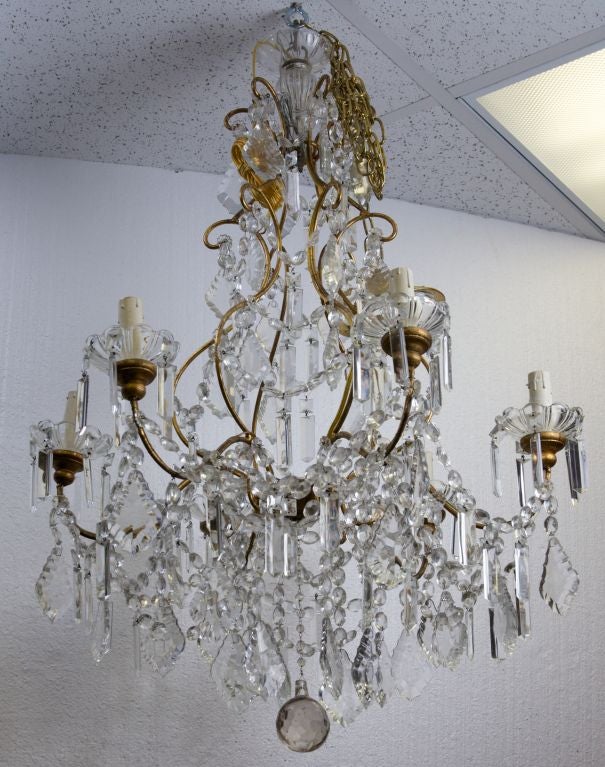 Large French crystal chandelier with a frame of brass tubing, 6 arms and candle style lights, glass bobeches, heavily embellished with a variety of crystal drops and pendants.