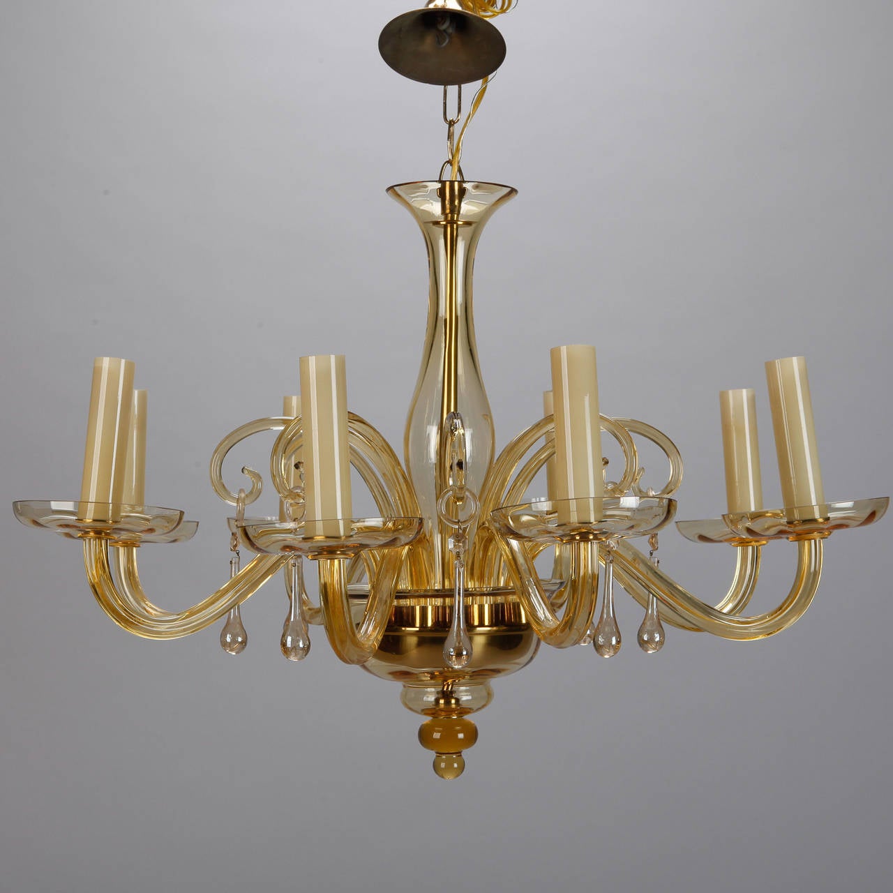 Circa 1940s Murano glass chandelier with eight candle style lights, amber colored hand blown glass center support, arms, bobeches and curled arms and dangling drops. New wiring for US electrical standards.