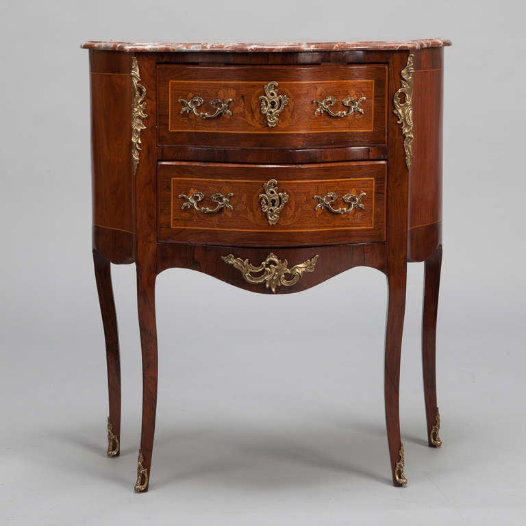 French two-drawer chest in Regence style with fancy brass mounts, inlay and burl work on sides and drawer fronts and a marble top, circa 1900. Leg repair on the back right leg - see last detail photo.