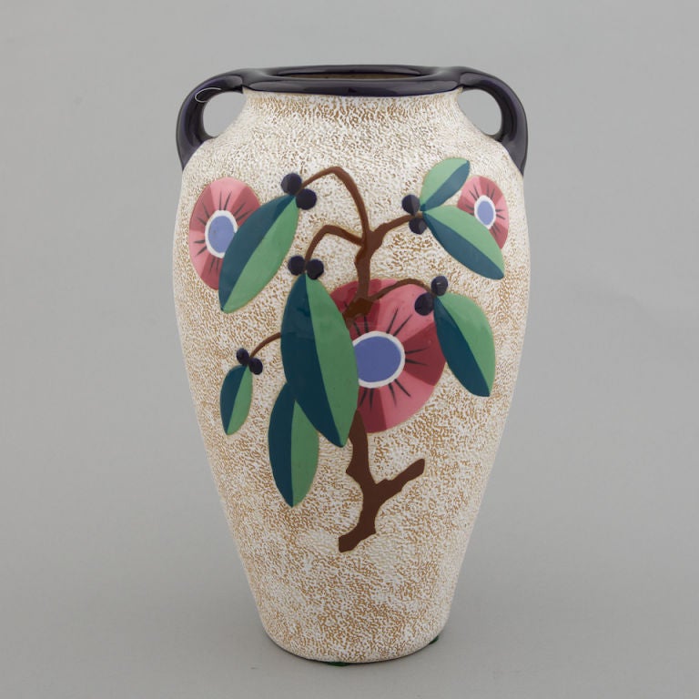 Tall handled vase has tan pebbled texture with black rim and handles and dramatic stylized floral decoration on front and back. Bottom is signed with Amphora Czechoslovakia.