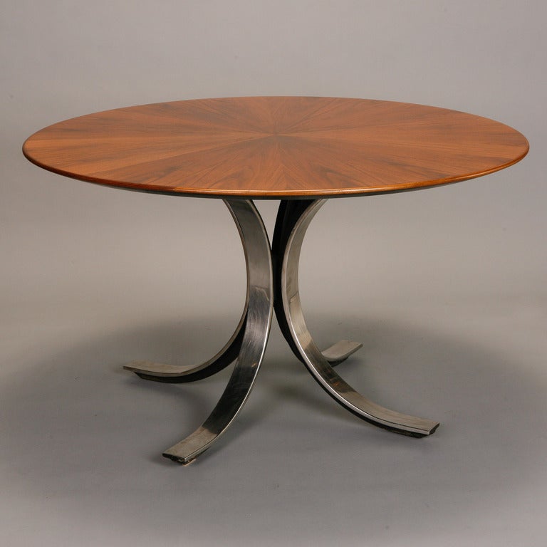 Circa 1960s Stow Davis table designed by Italian architect Osvaldo Borsani features a round walnut top with beautiful grain in a starburst pattern. Sculptural pedestal base of polished steel has four feet. Versatile 48” size works well as a compact