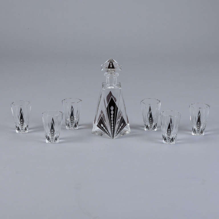 This Art Deco era decanter set is attributed to Karl Palda. The decanter has a pyramid shaped stopper and geometric shapes in black with a center stripe of etched dots and six matching glasses.