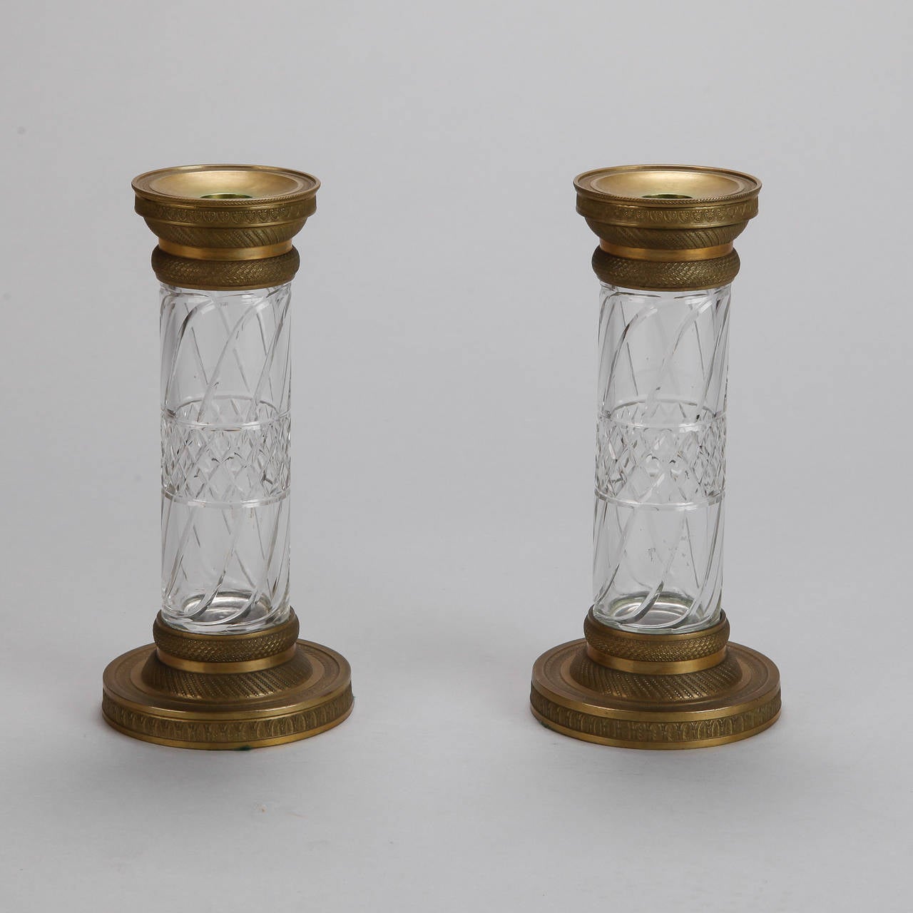 Circa 1880s pair of large bronze and cut crystal candle holders that could also function as a pair of vases.  Round, etched bronze bases and tops support clear cut crystal vessels. Sold and priced as a pair. Found in Paris.