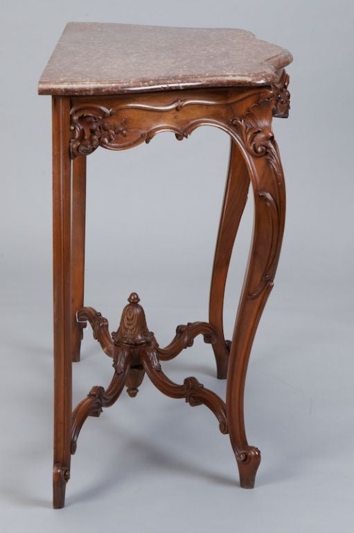 Elaborately carved French console with reddish brown and white marble top.  Center of apron has beautiful floral and foliate details and stretchers are joined with an intricately carved ornament.