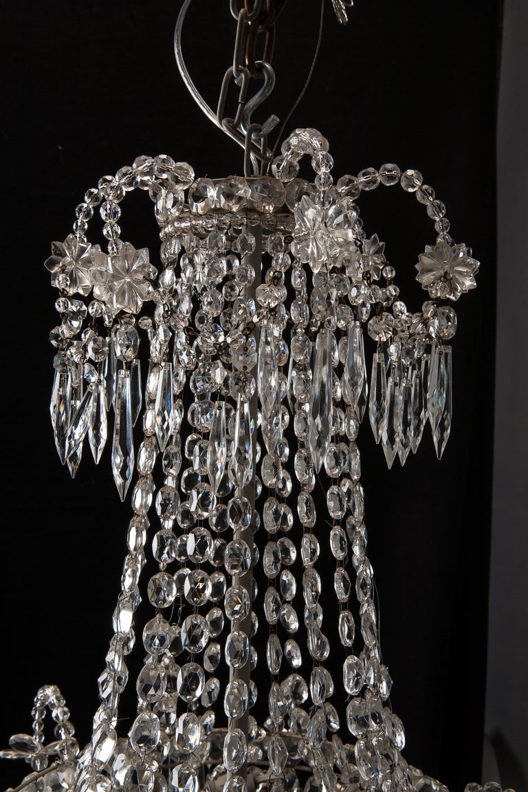 Circa 1900 Swedish chandelier has a top piece embellished with crystal flowers, dagger pendants and beads. Faceted crystal beads drape from a large bowl-shaped fixture highlighted with large crystals, dagger pendants, beaded arms and a faceted round