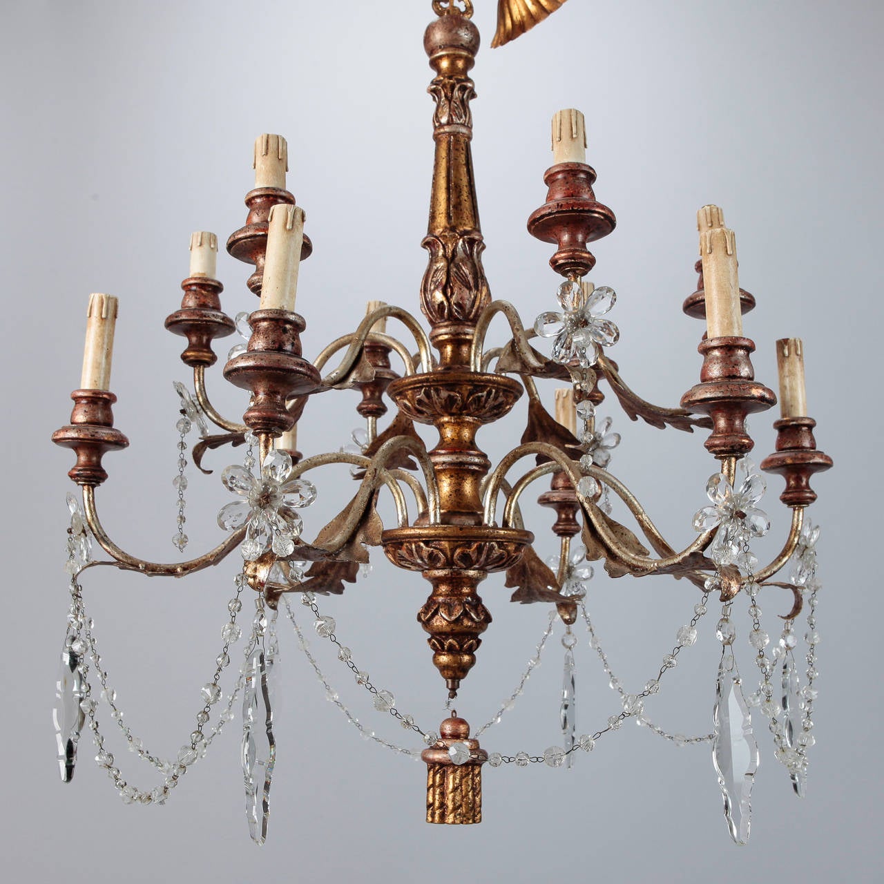 French twelve-arm chandelier has a giltwood and metal frame with candle style lights, and center wood tassel and is accented with several large clear crystal pendants, and beaded crystal swag, circa 1890s. 3” tall ceiling canopy included. New wiring