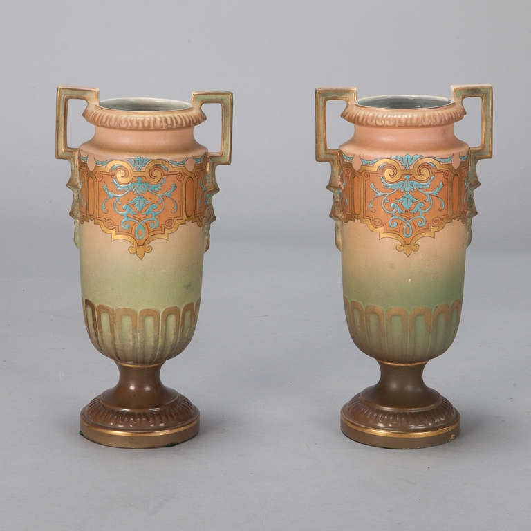 Circa 1940's pair of Art Nouveau style amphora vases with glaze in shades of apricot and green with blue and gold details. Sold and priced as a pair.
