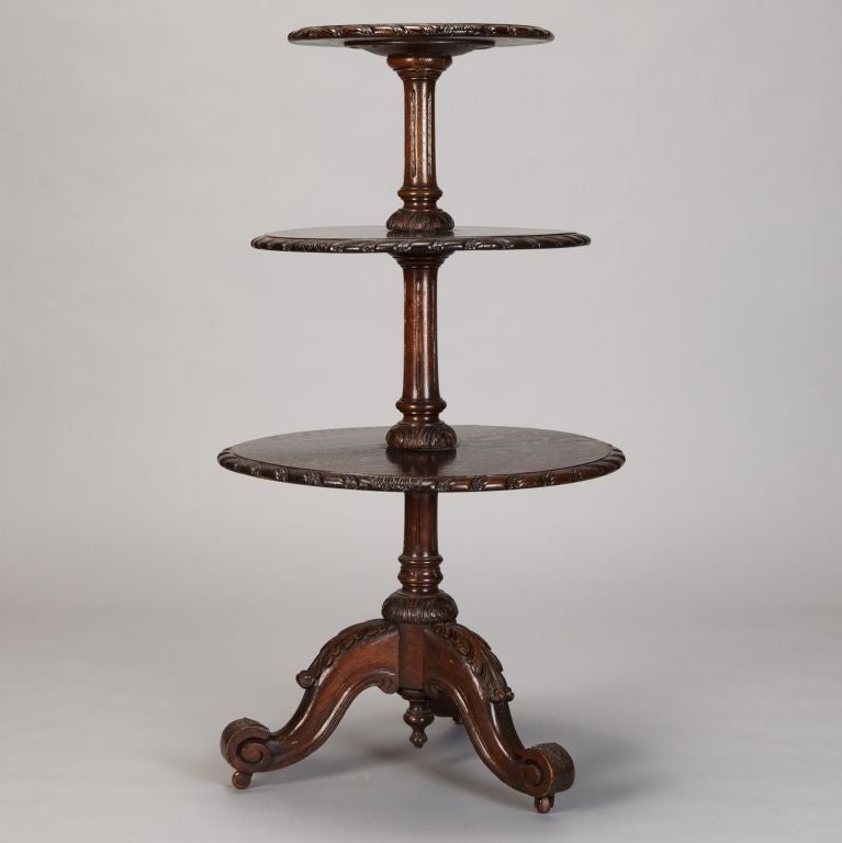 19th century English carved dumbwaiter table with carved and scrolled tri-foot base and three tiered, graduated table tops with carved rims.