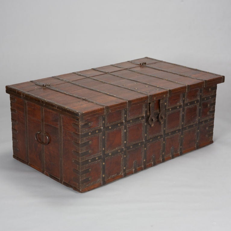 Adder wood dark stained trunk bound with iron strapping secured with brass studs. Double iron clasp.  This trunk would make a great coffee table with lots of storage. We have another, very similar trunk available that is even larger. Please inquire