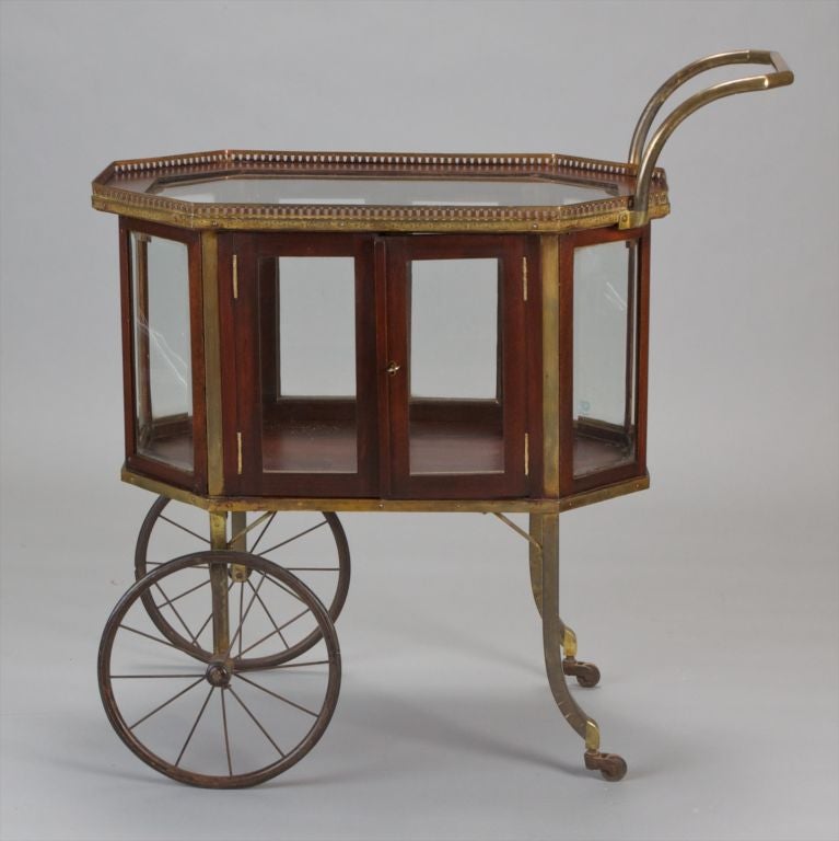 Circa 1825 English tea trolley made of wood and brass with beveled glass panels and functional wheels. Great piece to use as a side table, tea table or for display.