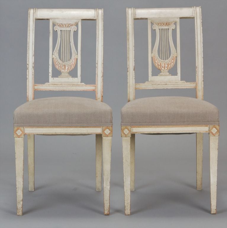 This set of four circa 1920 French lyre back chairs have an antique white painted finish, newly upholstered seats and tapered legs. <br />
<br />
Front Width:  17.5”<br />
Back Width:  14.5”<br />
Depth:  15”<br />
Height:  35”<br />
Seat