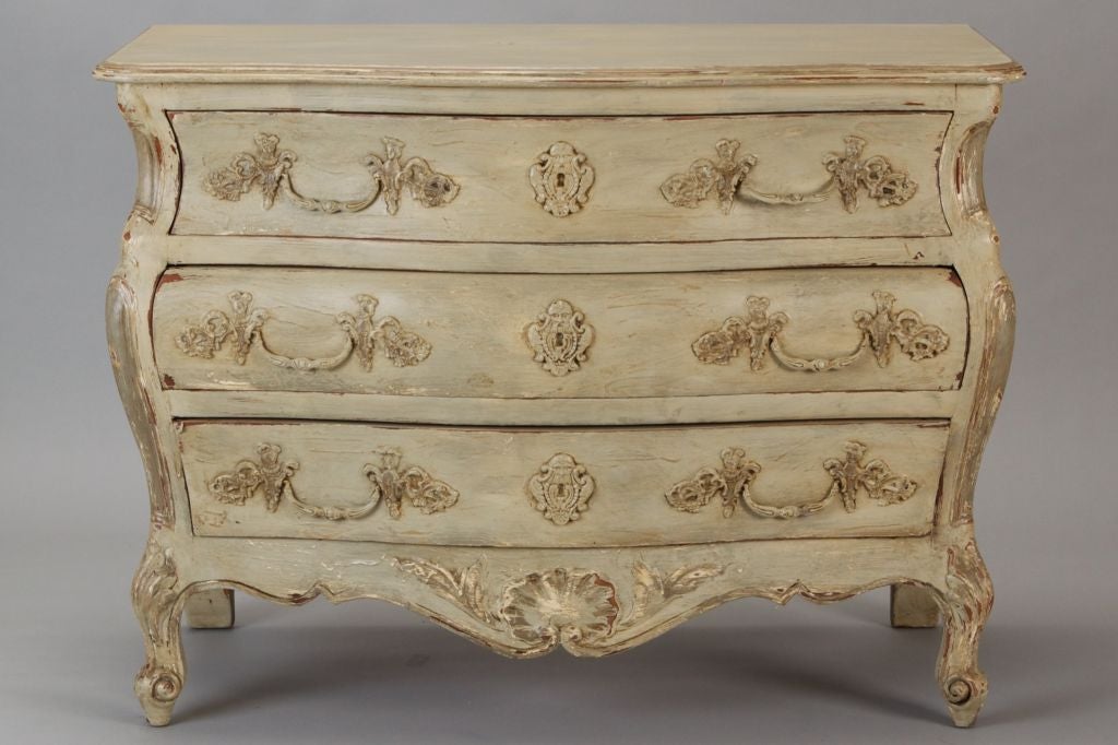 Turn of the century French Bombe-style chest has a cream / antique white painted finish. Classic curvy shape with beautifully detailed carving and three drawers.