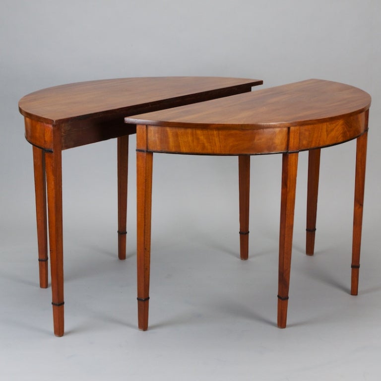 Classic pair of late 19th century English mahogany demilune tables. Clean lines, beautiful graining, ebonized trim, tapered legs.