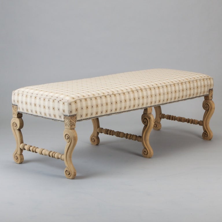 Turn of the century French bench is generously sized and features six carved, bleached oak legs and turned stretchers. Newly upholstered.