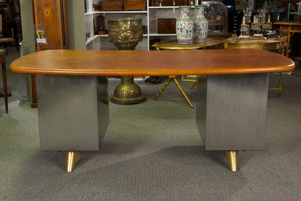 This 1950s era industrial desk has brass feet and drawer pulls. Kidney shaped leather covered desktop over a three drawer cabinet on the left side and a single drawer and locking file cabinet on the right.