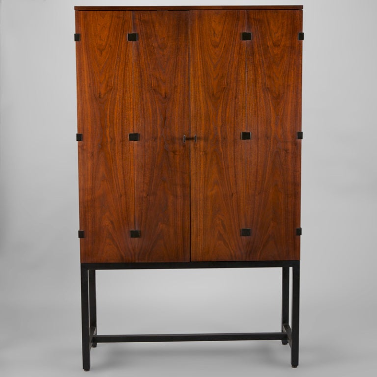 Tall walnut cabinet by Directional Gallery made during the time Kipp Stewart and Stewart MacDougal headed the design team. Black stained legs, beautifully grained walnut bi-fold doors with iron hardware. We also have a companion piece from this same