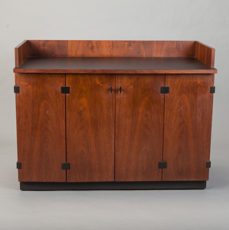 Walnut bar cabinet on casters by Directional Gallery made during the time Kipp Stewart and Stewart MacDougal headed the design team. Black stained base, beautifully grained walnut bi-fold doors with iron hardware, black laminate work surface. We