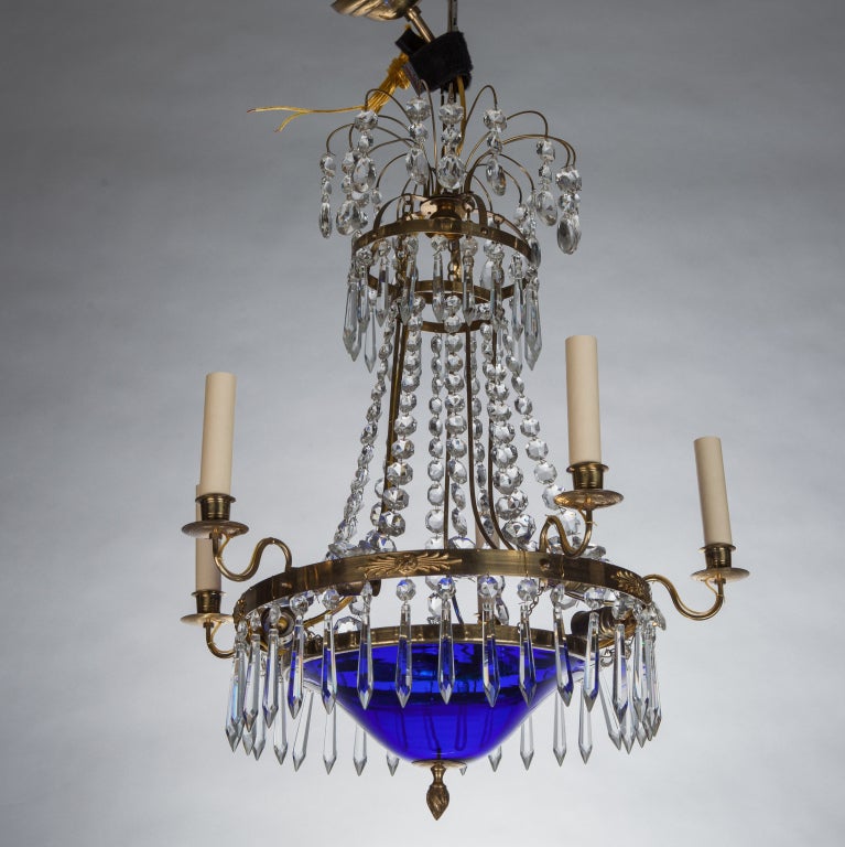 Late 19th century Swedish chandelier has five candle style lights, center cobalt blue glass bowl, faceted crystal swag and dangling dagger pendants. Rewired for US electrical standards. We have three other similar Swedish chandeliers with blue glass