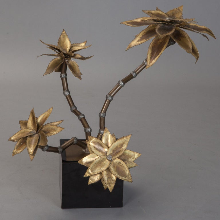 Dramatic floral sculpture mounted on black wood box and has four bamboo-like stems with four large brass layered petal blooms, circa late 1960s. Attributed to Maison Jansen, France.