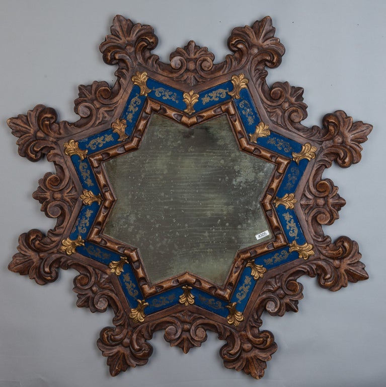 Carved wood star shaped frame French mirror has blue and metal details and intricately carved rays.