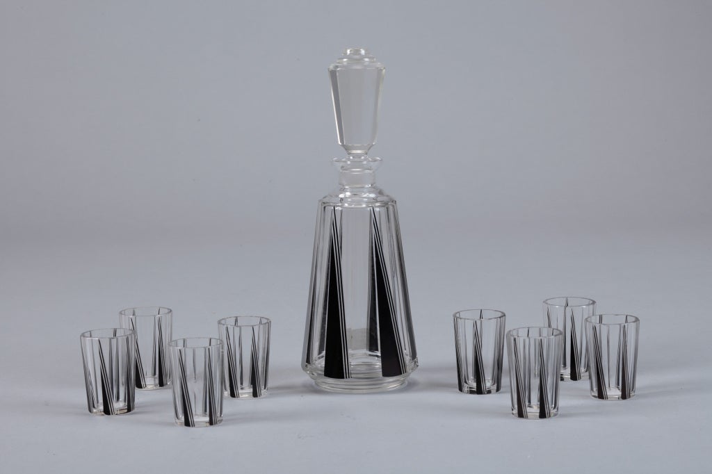 This circa 1930s decanter set has clear glass decanter embellished with black triangular pattern, tall stopper and 8 matching glasses. Attributed to Karl Palda.