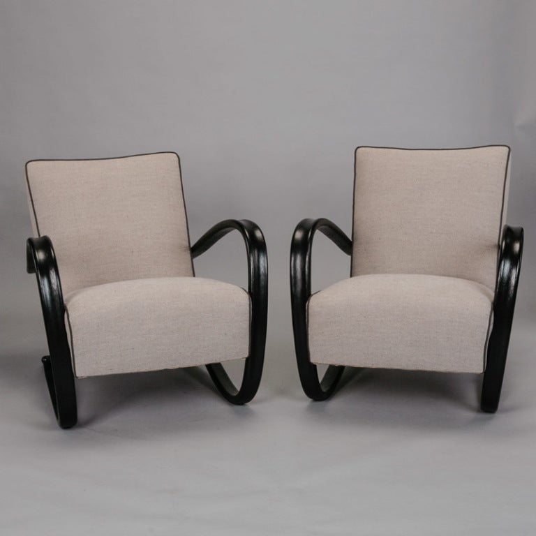 Circa 1940s pair of lounge chairs by Czech designer Jindrich Halabala. Chairs have curvy black wood frames, low slanted seats and new upholstery in a gray linen blend tweed with black welting. Seats are 15
