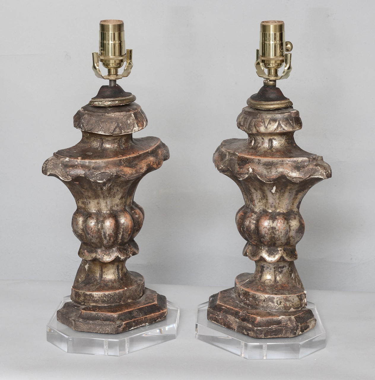 Pair of pricket bases, of silver giltwood, each carved into an urn shape with fluted socle on round foot.  Lamped on custom bases of Lucite.

Stock ID: D7230