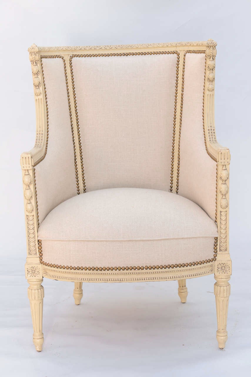 Pair of bergeres, having a painted frame with natural wear to finish; each bowed gadrooned crestrail continues into downswept arms, outcarved with graduated husking, finishing with scrolls, similarly carved terminals flank its crown seat, on