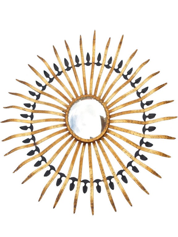 Very decorative sunburst, of painted and gilded iron, having a convex mirror center, surrounded by a multitude of narrow metal 