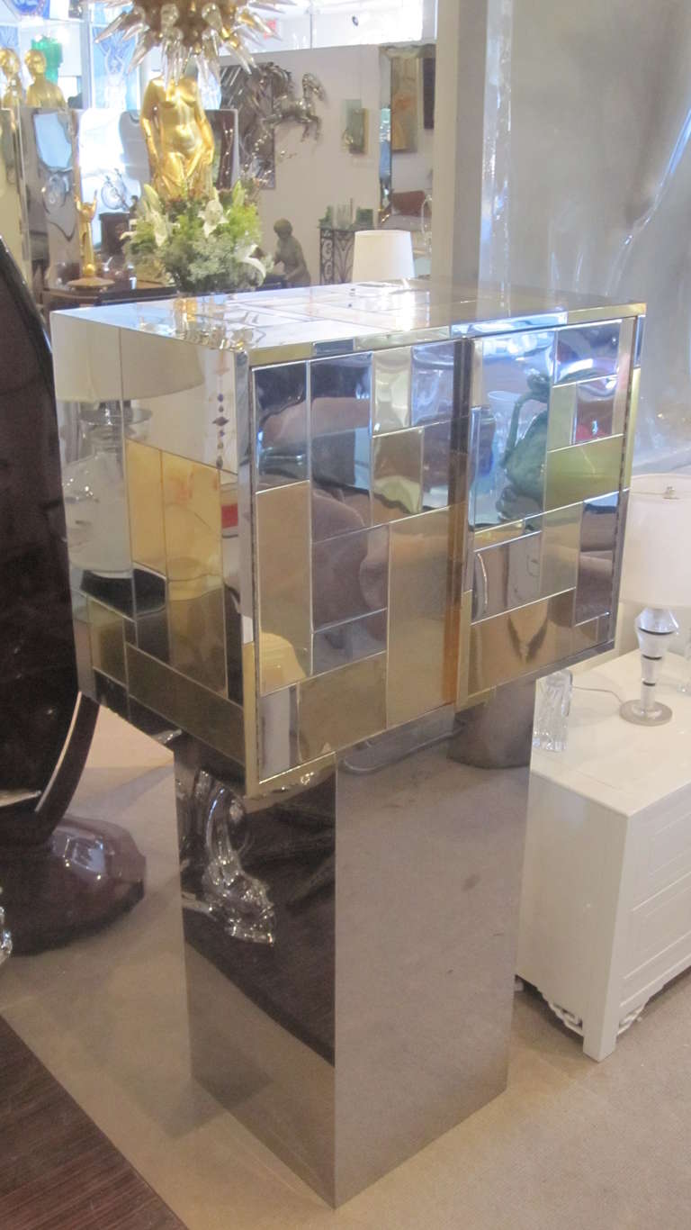 This Paul Evans Cityscape Cabinet has two doors, and three interior drawers. Clad in a patchwork of chrome and brass tiles it was made in the 1970s by Evans' own company Directional Furniture. The cabinet is displayed on a pedestal, but not