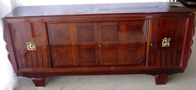 Alluring French art deco sideboard of beautiful  French lacquered palisander wood with marquetry and scalloped sides. Adorned with stunning bronze medallions, bronze hardware, and bronze sabot treatment to the legs. Created Circa 1935 by Maison