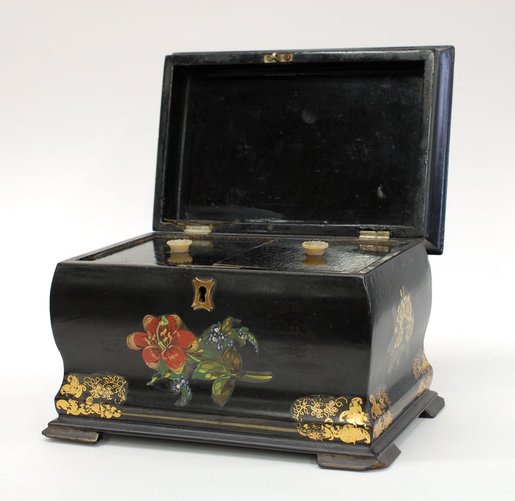 A handsome shaped antique Papier Mache inlaid with mother-of-pearl along with gilt and hand painted floral decoration Tea Caddy. Carved mother-of-pearl handles to compartment lids.  Original metal foil linings. No maker's mark.