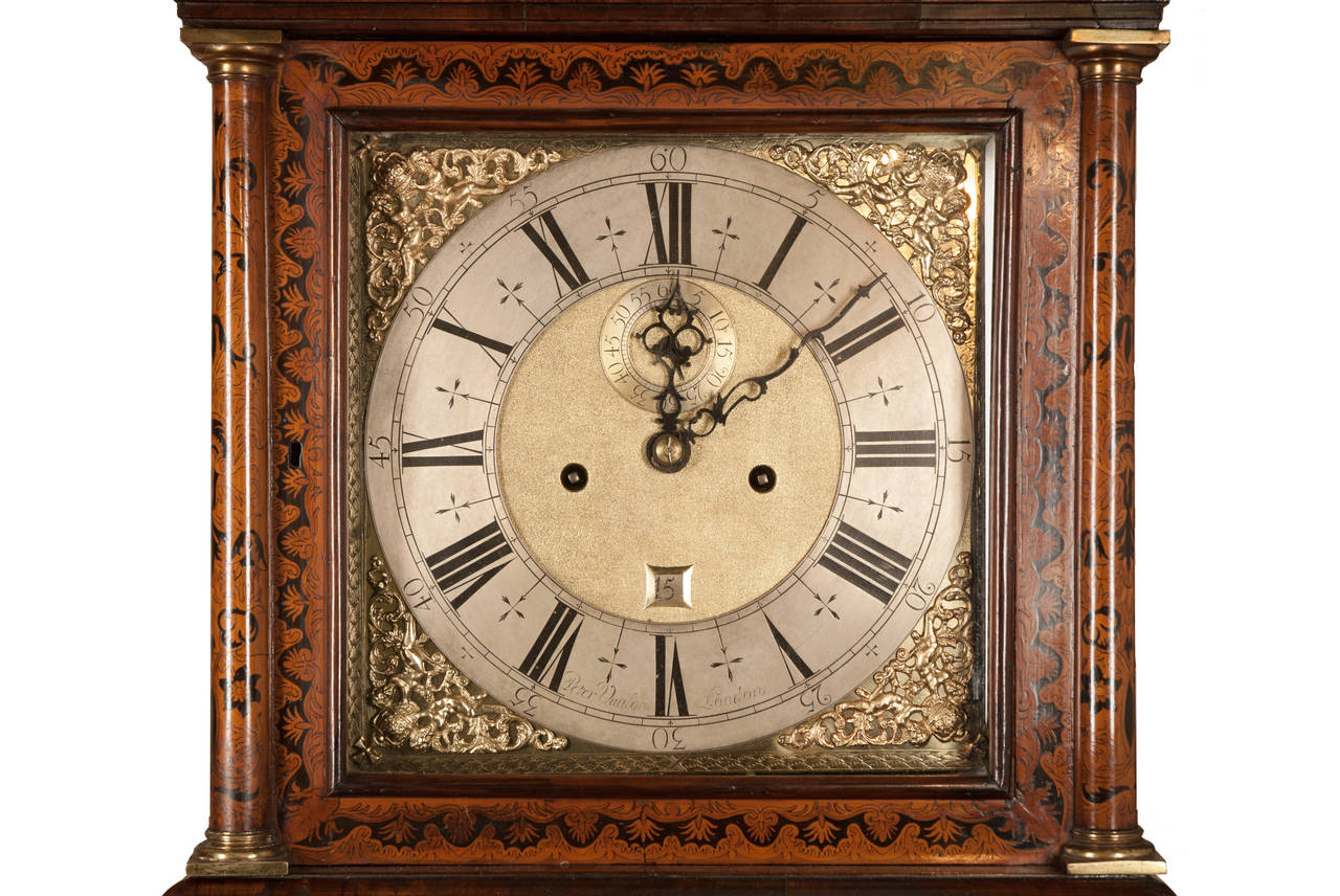 A Queen Anne longcase clock in a walnut inlaid marquetry case in what i believe to be the Arabesque style. It is signed on the silvered chapter ring Peter Vaulou, London. (We have not been able to identify this maker as yet as the signature is