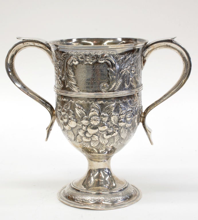 An antique English George III Sterling Silver Loving Cup with a later inscription from Northampton and dated 1860.   The body is decorated with floral repousse work. Weight: 328 grams