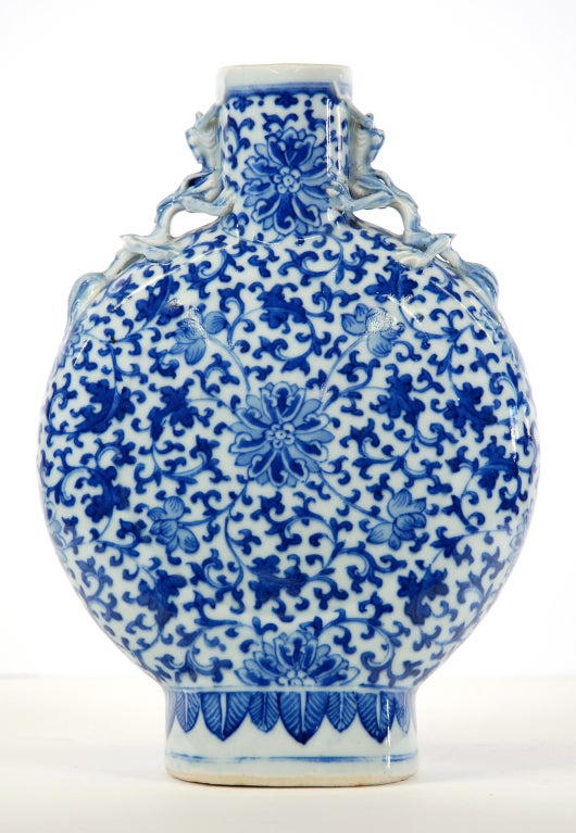 An antique Chinese Porcelain Moon Flask from the late l9th century with hand painted decoration.  Blue & white with floral decoration and animal heads to either side of the opening at top.  No maker's mark.