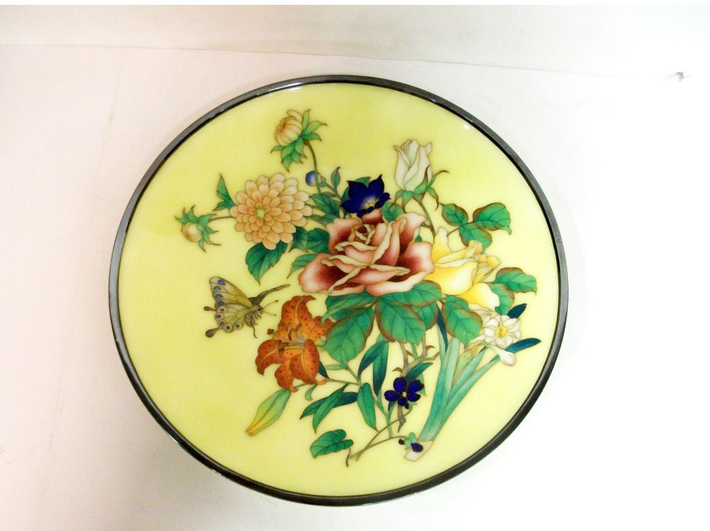A floral designed Japanese cloisonne small charger with a hovering butterfly.  The whole on an unusual yellow ground.  Signed on base: the mark of Ando.
