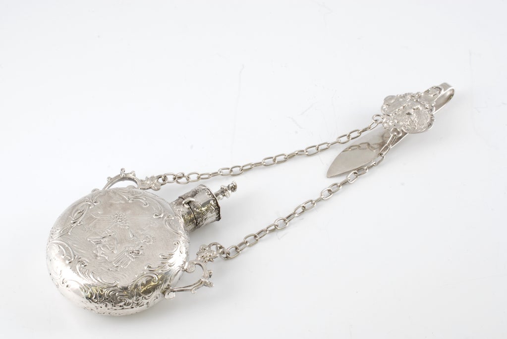 Ornate Sterling Silver Perfume with chain and hook for a chatelaine.  Has London import marks for 1889 so is probably German.  The decoration shows a man and a woman in two different poses in a garden.