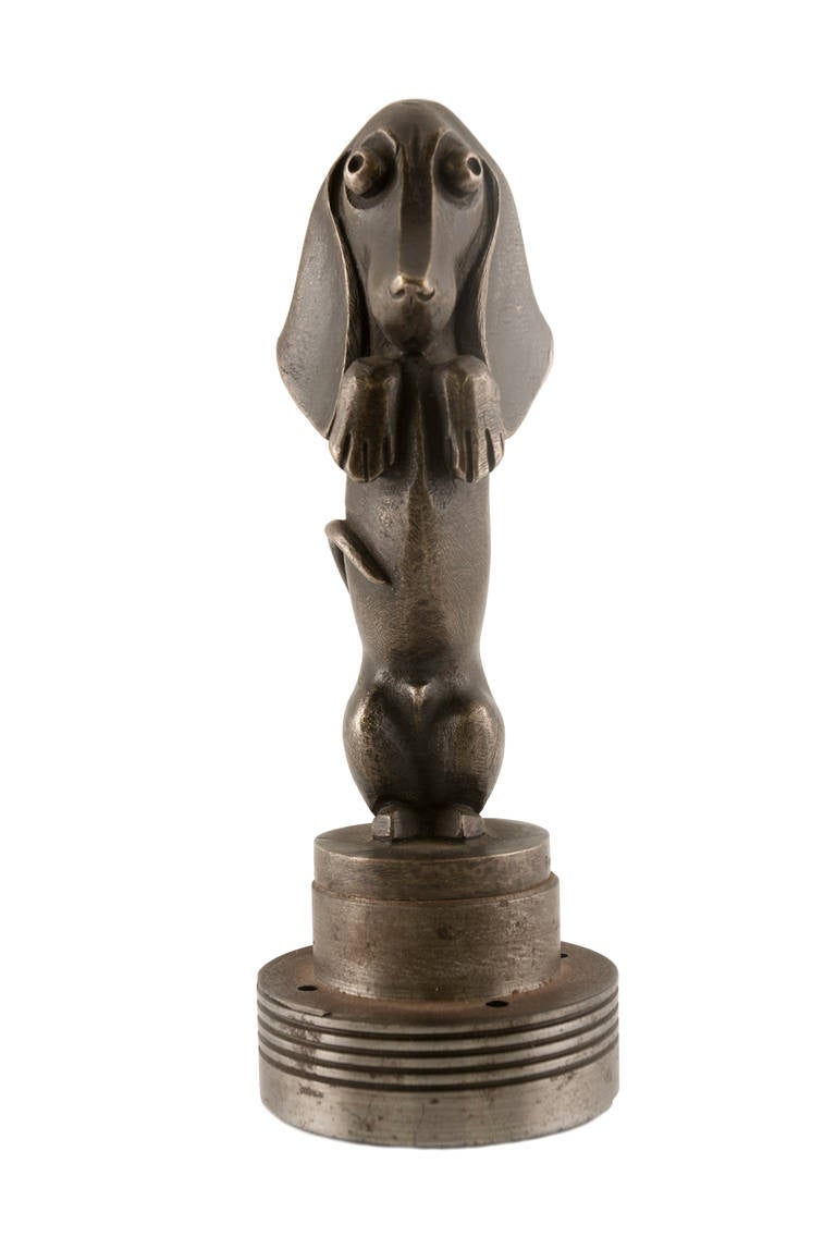 This is a stylized Bronze animal figure of a begging Dachsund in the form of
a Car Mascot.  It is signed on the base Becaurel (?)and the foundry Etling, Paris.
This is one of two  Dachsund Bronze Car ascots that we have for sale.