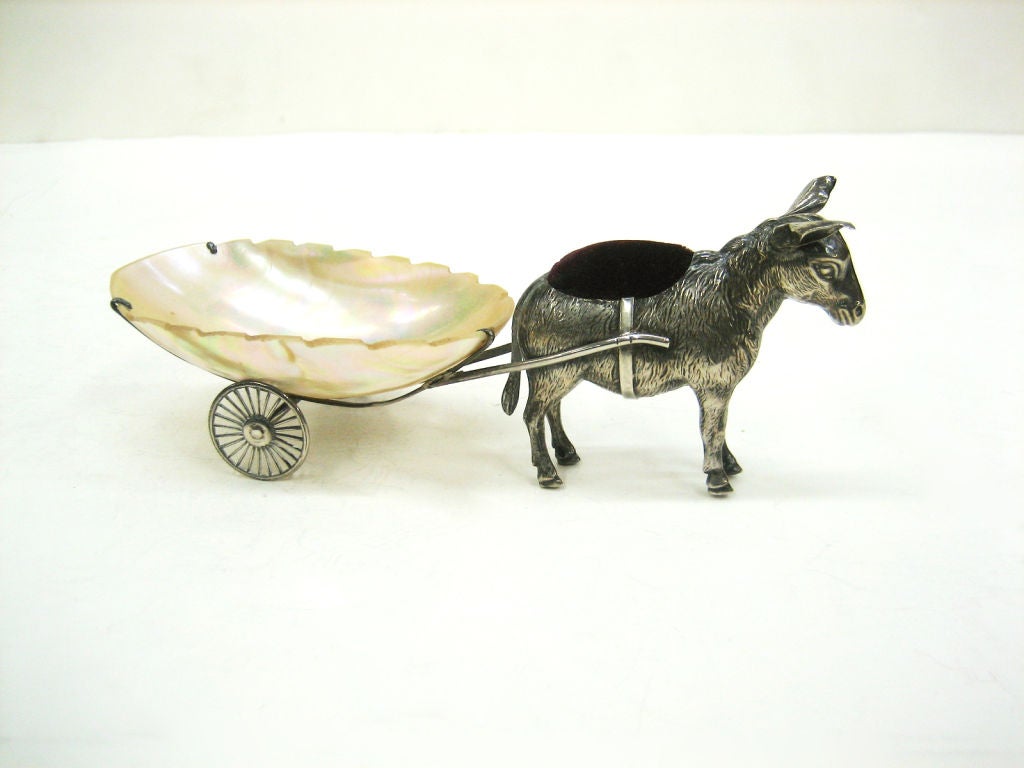 A Pin Cushion in Sterling Silver of a Donkey pulling a mother-of-pearl cart on silver wheels.  The wheels move.  This is a very rare object.