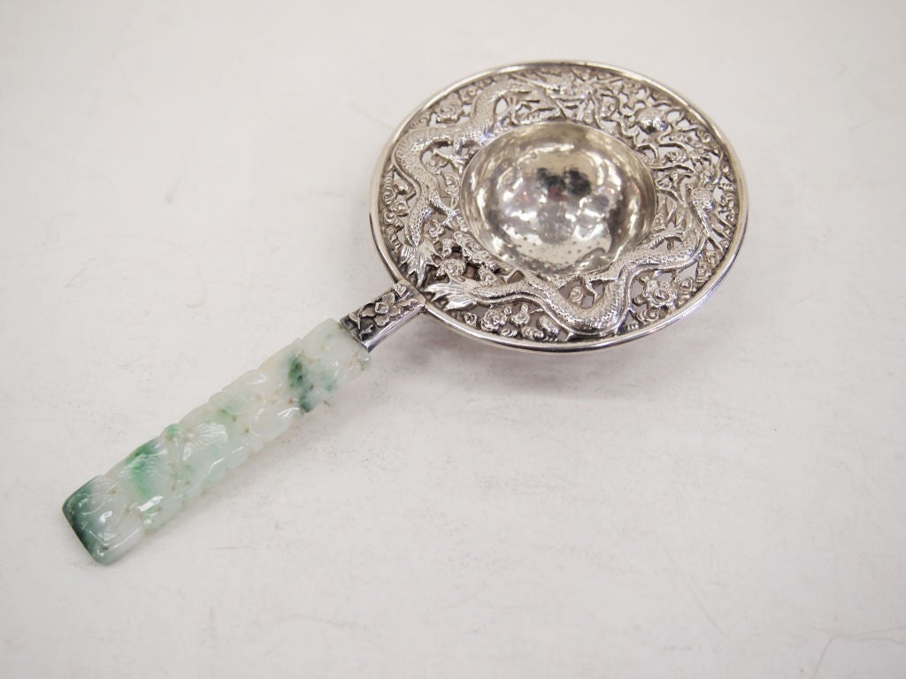 A very ornate Tea Strainer in Sterling Silver with two dragons writhing around the rim.  <br />
The ornate handle is carved jadeite.  Signed: Chin Sterling