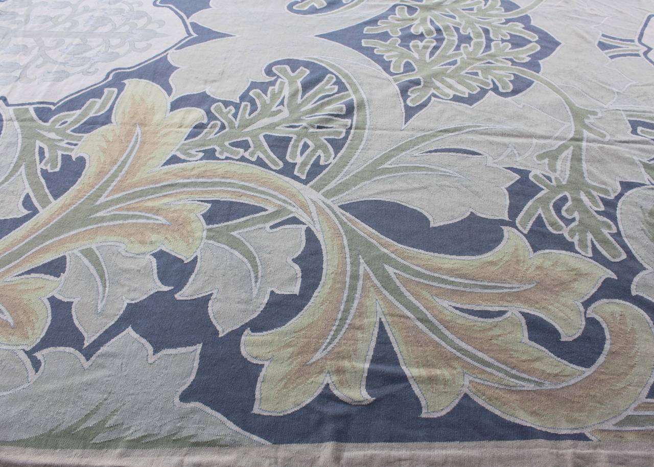 Early 20th Century tapestry with foliage rendered in soft green, yellow and blue tones.