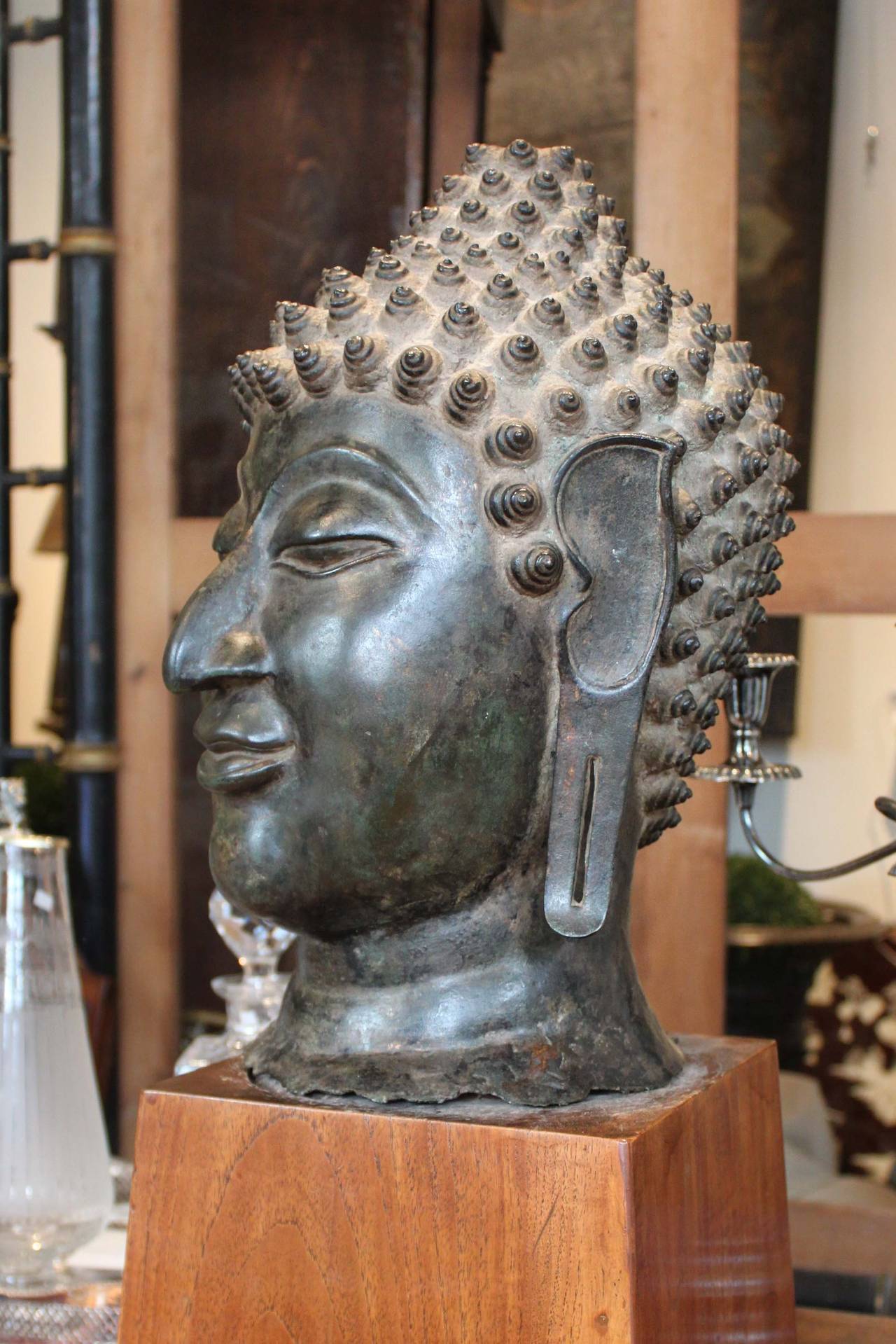 Antique bronze Buddha head in the Chien Seng style Sakyamuni, South East Asian. Face displays serene expression with downcast eyes below arched eyebrows with curled headdress Ushnisha. A fantastic piece complete with wooden base.