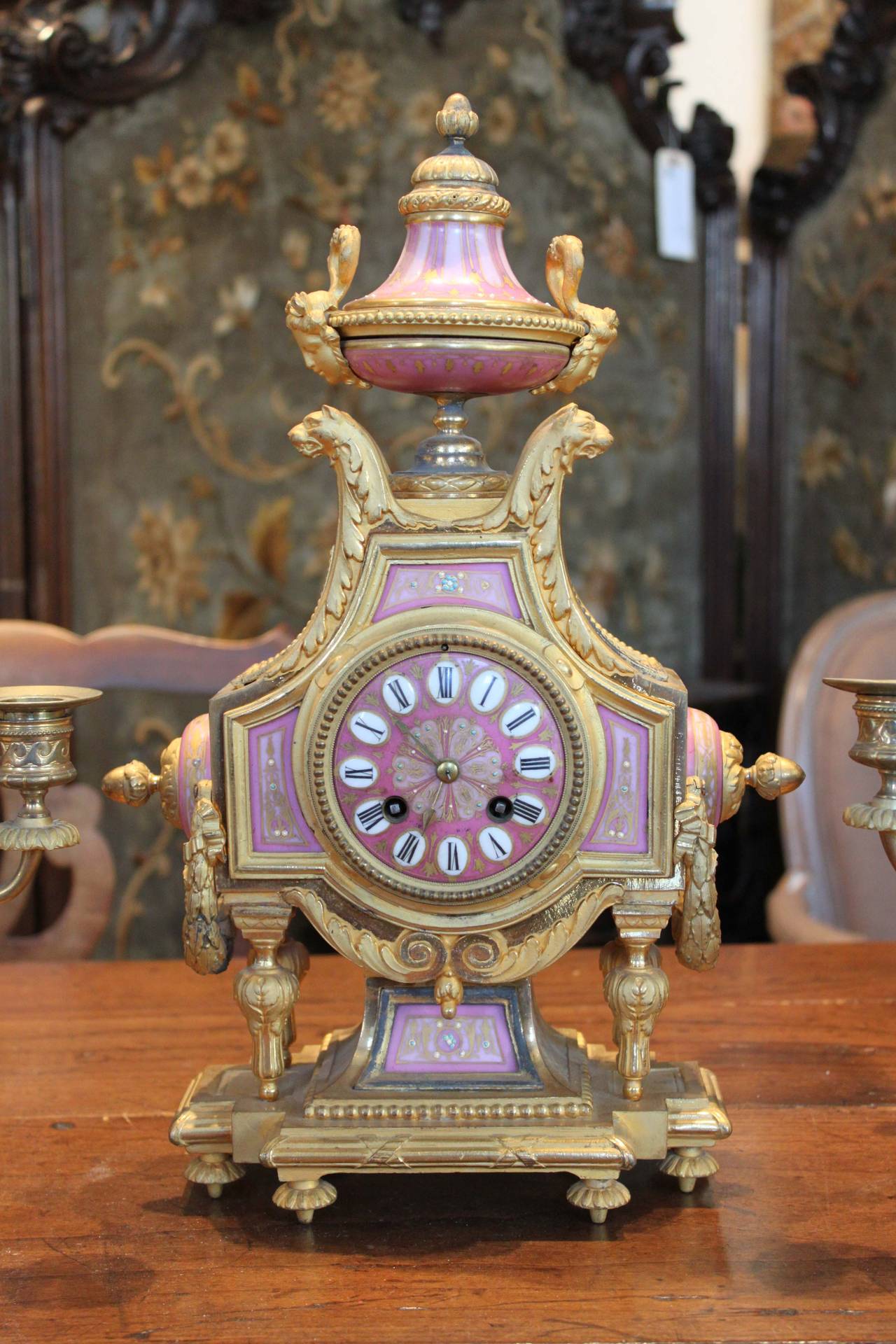 A 19th century French gilt ormolu clock accompanied by a pair of candelabra with pink sèvres plaques. 

Clock: 16