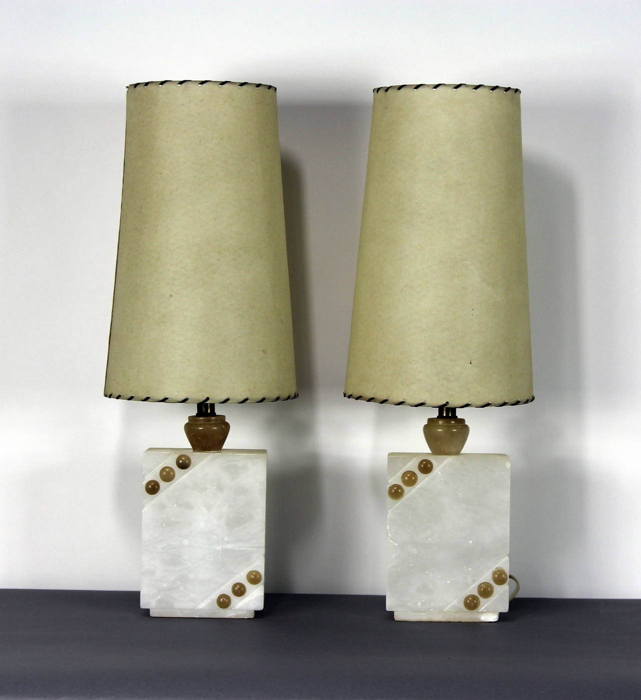 A superb pair of 1950s Italian modernist table lamps crafted from natural alabaster with tan alabaster accents and tan alabaster stems. These rare sculptural lamps have retained their original laced parchment shades.